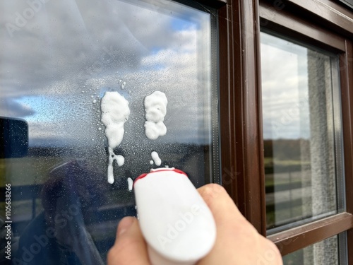 cleaning a window with a window cleaning scraper side view