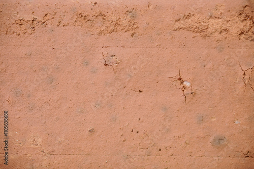 Close-up view of a textured surface, likely a brick or stucco, exhibiting a light reddish-brown color.