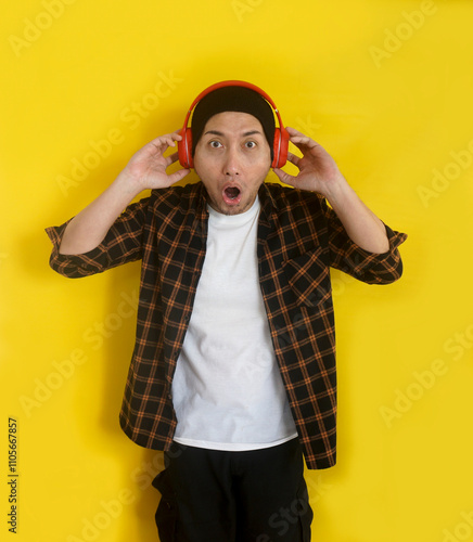 Young Man Wear Beanie Hat Listening Music From Headphones With Shocked Expression