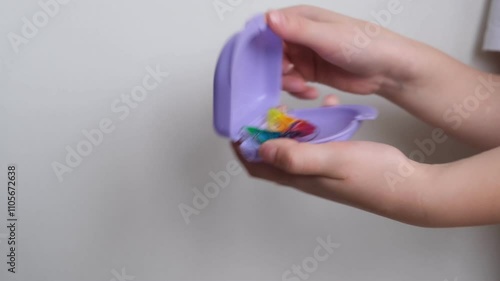 A dental plate for children of rainbow color. The child holds orthodontic braces in his hands to align the teeth and expand the jaw.	