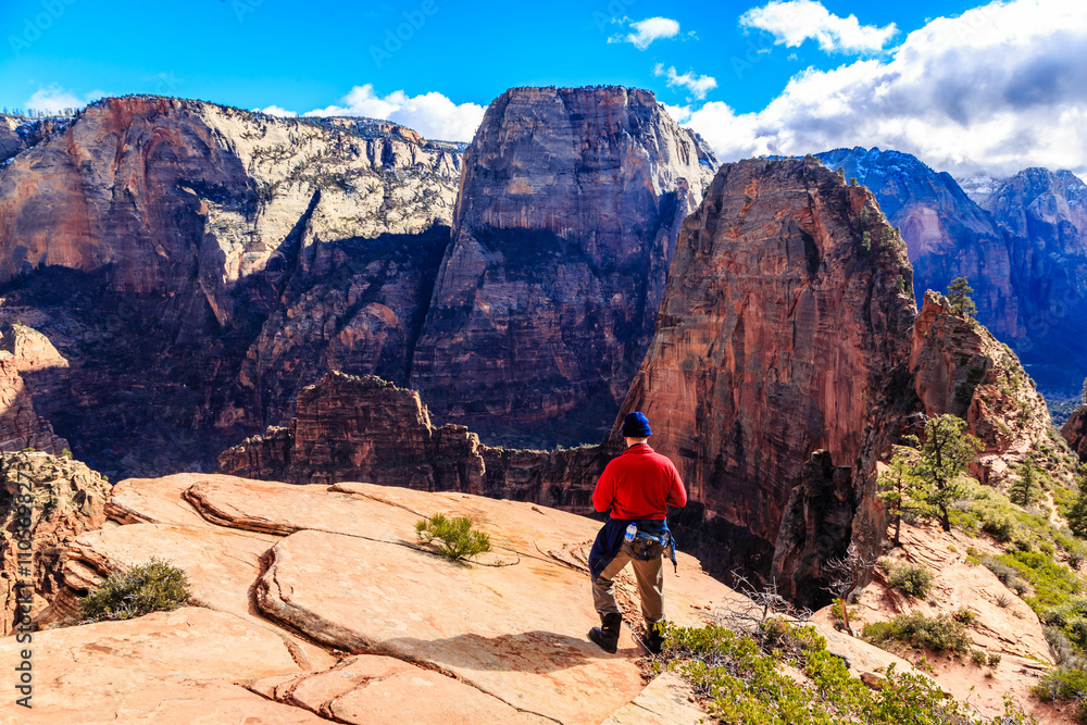 A man stands on a rocky mountain top, looking out over the landscape A man stands on a rocky mountain top, looking out over the landscape