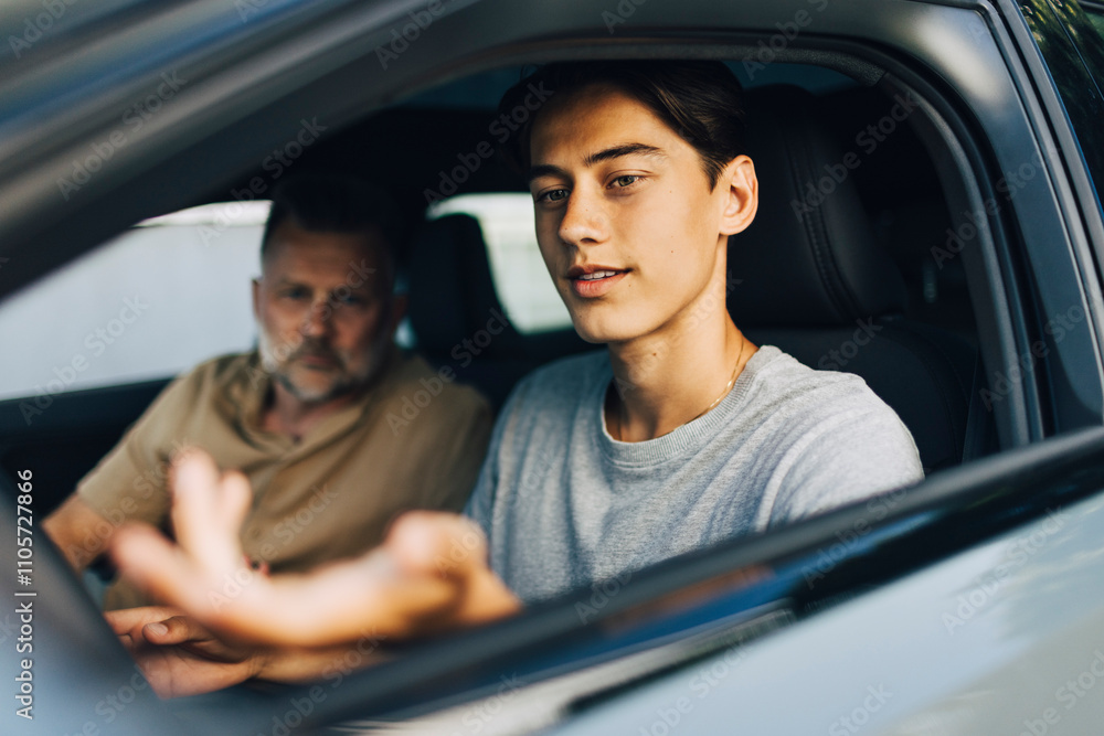 Young man getting driving lessons from father while sitting in car Young man getting driving lessons from father while sitting in car
