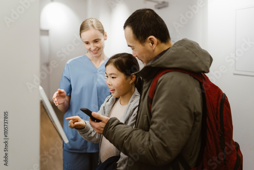 Girl booking appointment while using kiosk with father and nurse in hospital