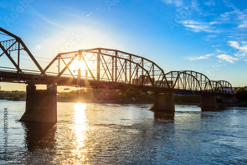 A bridge spans a river with a beautiful sunset in the background