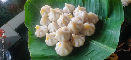 Maharashtrian sweet of Modak that is offered to Lord Ganesh, garnished with kesar (saffron) to be had with Ghee bowl and Lord Ganpati in the background.