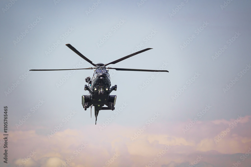 Front view of a military helicopter is hovering in the sky at an airshow. Cloudy sky in the background. Front view of a military helicopter is hovering in the sky at an airshow. Cloudy sky in the background.