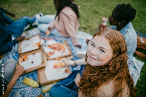 High angle portrait of smiling teenage girl eating pizza with friends at park photo