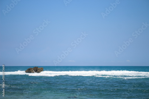 Soft waves of blue sea with foam on golden white sandy beach. Wave background