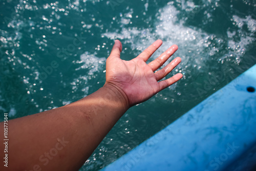 hands playing with sea waves when riding a boat