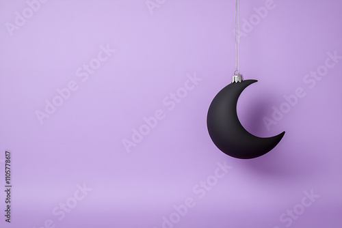 Matte black crescent moon ornament on a twilight purple background photo