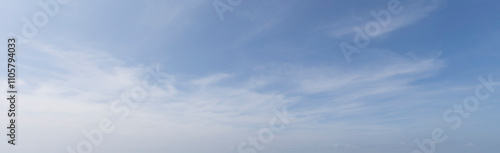 Wide-angle landscape photograph capturing a calm blue sky with soft white cirrus clouds, evoking tranquility and serenity.