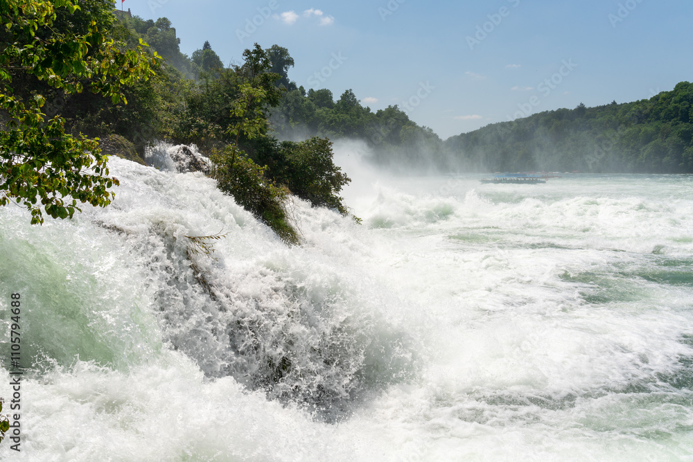 Fototapeta premium The Rhine Falls on a beautiful summers day. Spectacular view with white foaming water, spray and mist.
