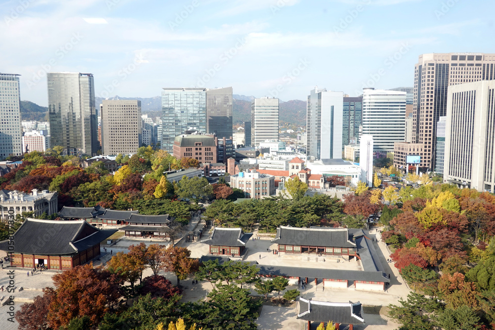 Fototapeta premium Autumn scenery of Deoksugung Palace, the palace of the Joseon Dynasty, surrounded by large buildings in the heart of Seoul, Korea