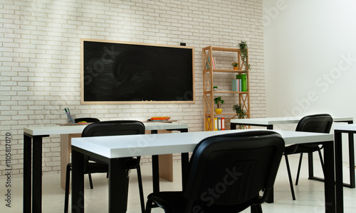 Empty modern school classroom with desks, chairs and chalkboard at daylight, workspace for learning and teaching. Side angle view.