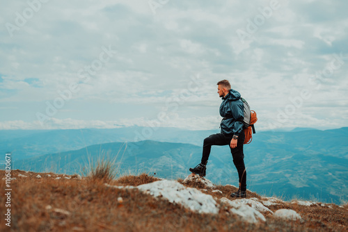 A male traveler standing on the mountain top during the hike, adventure travel. High quality photo