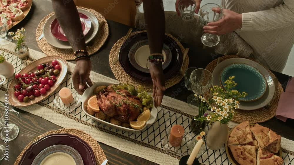 High angle shot of unrecognisable members of multi-ethnic family getting ready for festive lunch arranging table with glasses and food High angle shot of unrecognisable members of multi-ethnic family getting ready for festive lunch arranging table with glasses and food