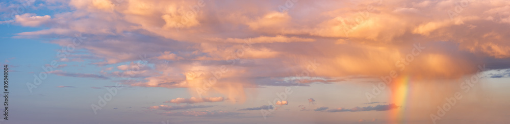 Panoramic background of sky with rain shower, rainbow and orange clouds at sunset Panoramic background of sky with rain shower, rainbow and orange clouds at sunset