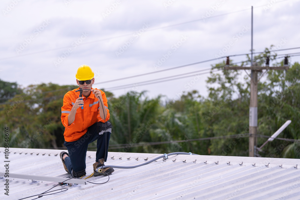 Technician in an orange safety uniform and helmet handling an electrical cable on a rooftop. Represents safety, professionalism, and expertise in renewable energy installations and maintenance work. Technician in an orange safety uniform and helmet handling an electrical cable on a rooftop. Represents safety, professionalism, and expertise in renewable energy installations and maintenance work.