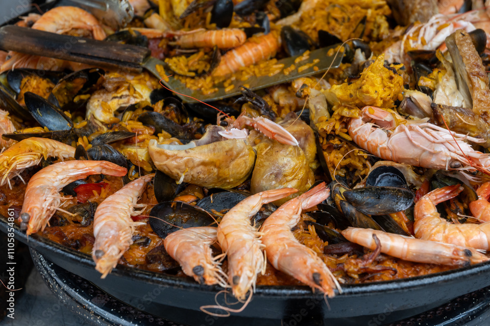 Street food in France, fresh prepared colorful paella with rice and sea food in big pan on street market ready to eat Street food in France, fresh prepared colorful paella with rice and sea food in big pan on street market ready to eat