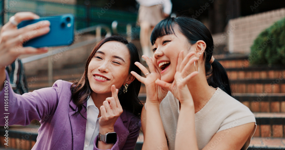 Women, selfie and together on stairs in city for heart sign, partner or smile for post in street. Business people, friends and photography with love symbol, funny or emoji for social media in Japan Women, selfie and together on stairs in city for heart sign, partner or smile for post in street. Business people, friends and photography with love symbol, funny or emoji for social media in Japan