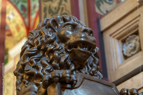 A detailed bronze lion sculpture stands prominently against ornate, colorful wall decorations, showcasing artistic craftsmanship within a historic space photo