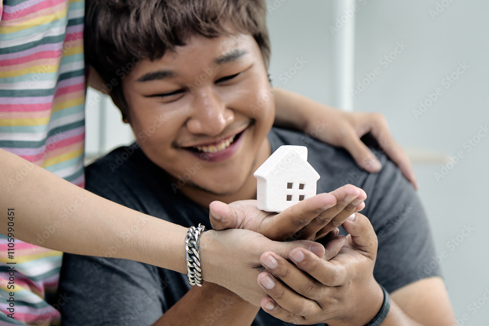 Close-up of a joyful individual holding a miniature house model symbolizing creativity and teamwork Close-up of a joyful individual holding a miniature house model symbolizing creativity and teamwork
