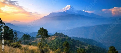 A scenic view of a mountain range with a snow-capped peak in the distance. The sky is a beautiful blue with some clouds, and the sun is setting in the distance, casting a warm glow on the landscape.