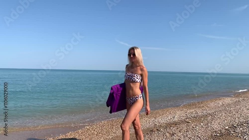 Beautiful slim sexy blonde woman in sunglasses floats on an inflatable mattress in the sea. Enjoys, sunbathes, smiles.
