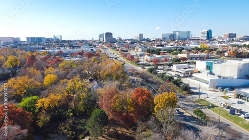 Foto Yellow red orange fall foliage over urban park along Belt Line Road with office
