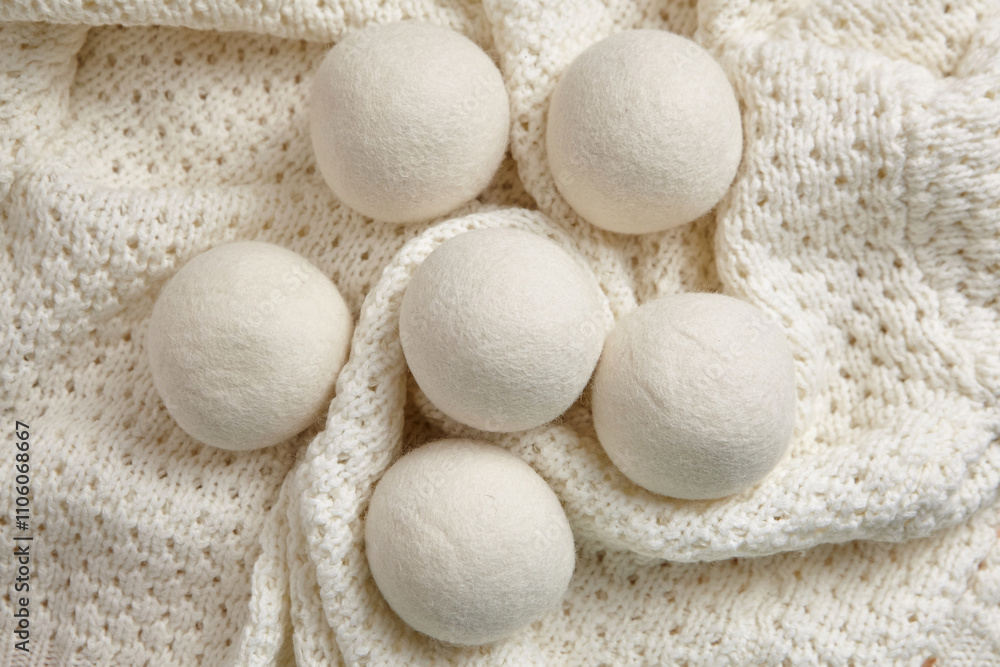 Six wool dryer balls placed on a soft, textured white knitted blanket, top view, flat lay. An eco-friendly, reusable alternative for reducing static and wrinkles in laundry Six wool dryer balls placed on a soft, textured white knitted blanket, top view, flat lay. An eco-friendly, reusable alternative for reducing static and wrinkles in laundry