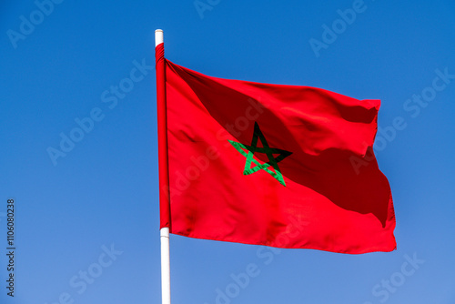 Moroccan flag waving with a green star under a clear blue sky