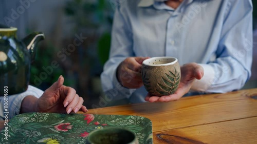 hands close up home happy old age elderly couple pleasant memories leisure in old age wife brings tea for her husband sitting at the table care in old age pours tea into cups