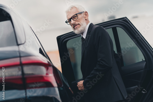 Senior businessman entering a car on city street showcasing professionalism and travel concept