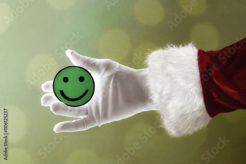 Santa Claus hand holding green smiley face cutout isolated background