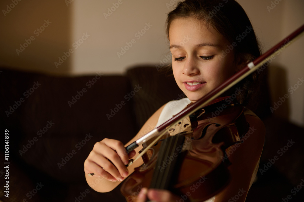 Young girl playing a violin with focused expression and joy Young girl playing a violin with focused expression and joy