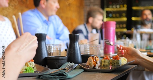 Modern dining with Japanese cuisine. Group enjoying Japanese cuisine with sushi rolls served fresh on table. Harmony of taste and presentation makes this moment ideal for sharing culinary delights.