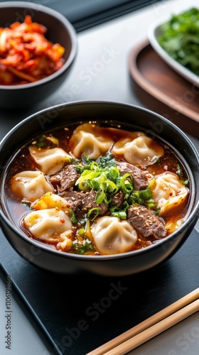 Delicious bowl of beef and dumpling soup with green onions and side of spicy ...