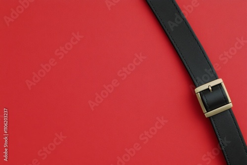 Black leather belt on a solid red background showcasing classic style and ele...