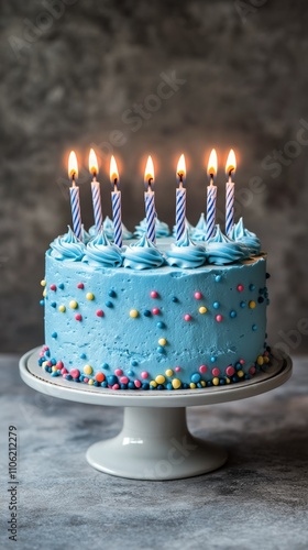 Delicious blue birthday cake with lit candles and colorful sprinkles during a...