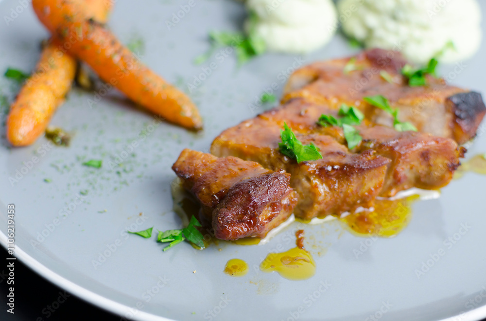 Roasted pork belly with glazed carrots and cauliflower puree in a grey plate Roasted pork belly with glazed carrots and cauliflower puree in a grey plate