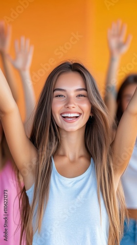 Beautiful young woman smiling joyfully against a vibrant orange backdrop in b...