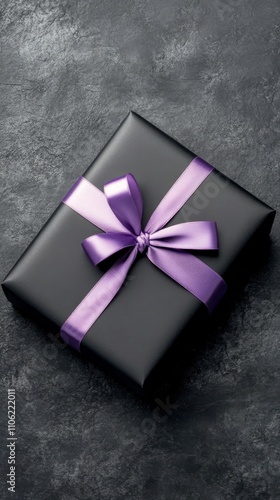 Elegant black gift box with purple ribbon wrapped on textured background