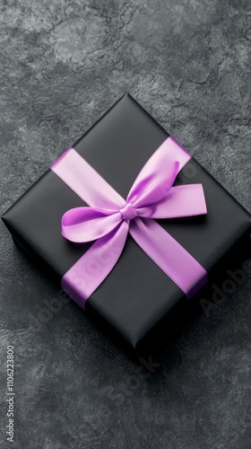 Elegant black gift box with purple ribbon wrapped on textured background