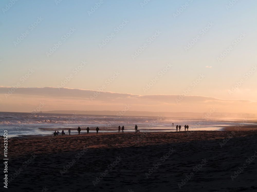 Sandy beach and walkers in the distance with back light in Balmedie - Aberdeenshire - Scotland - UK Sandy beach and walkers in the distance with back light in Balmedie - Aberdeenshire - Scotland - UK
