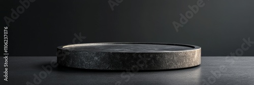 Minimalistic black display stand with soft lighting against a textured dark wall