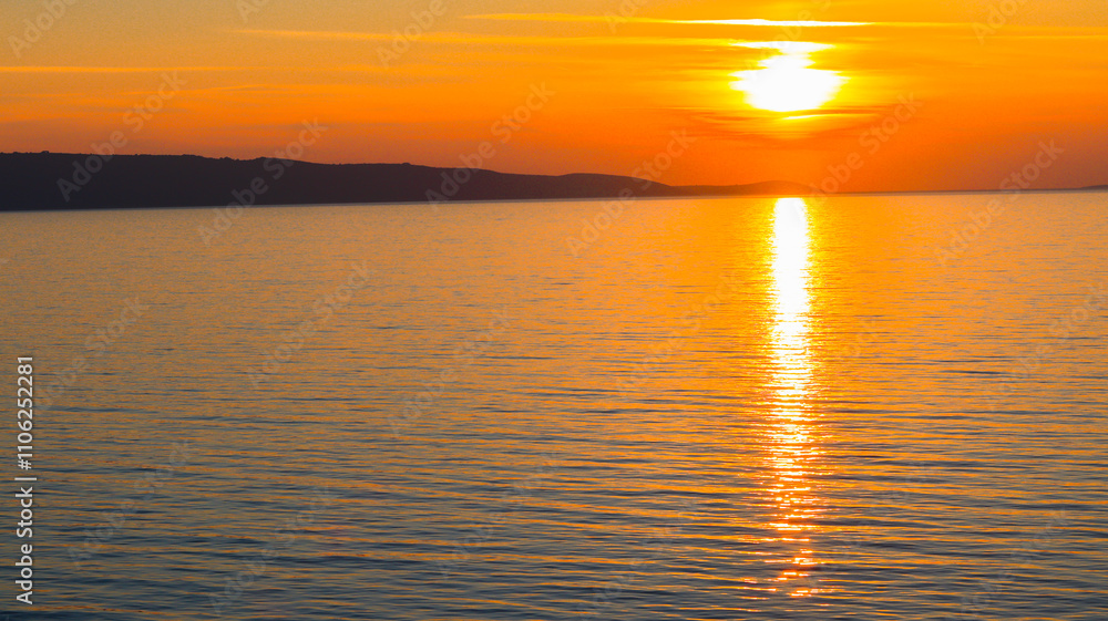 Obraz premium Pôr do sol deslumbrante no mar Mediterrâneo, com as cores quentes do céu refletindo na água tranquila, criando uma atmosfera relaxante e serena ao final do dia