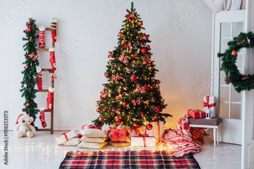 Christmas tree with gifts decorated with red toys in the interior