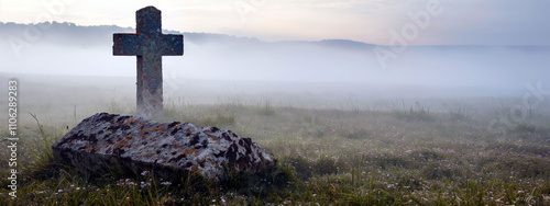 Solitary stone cross in a misty field during St. Swithin's Day at dawn photo