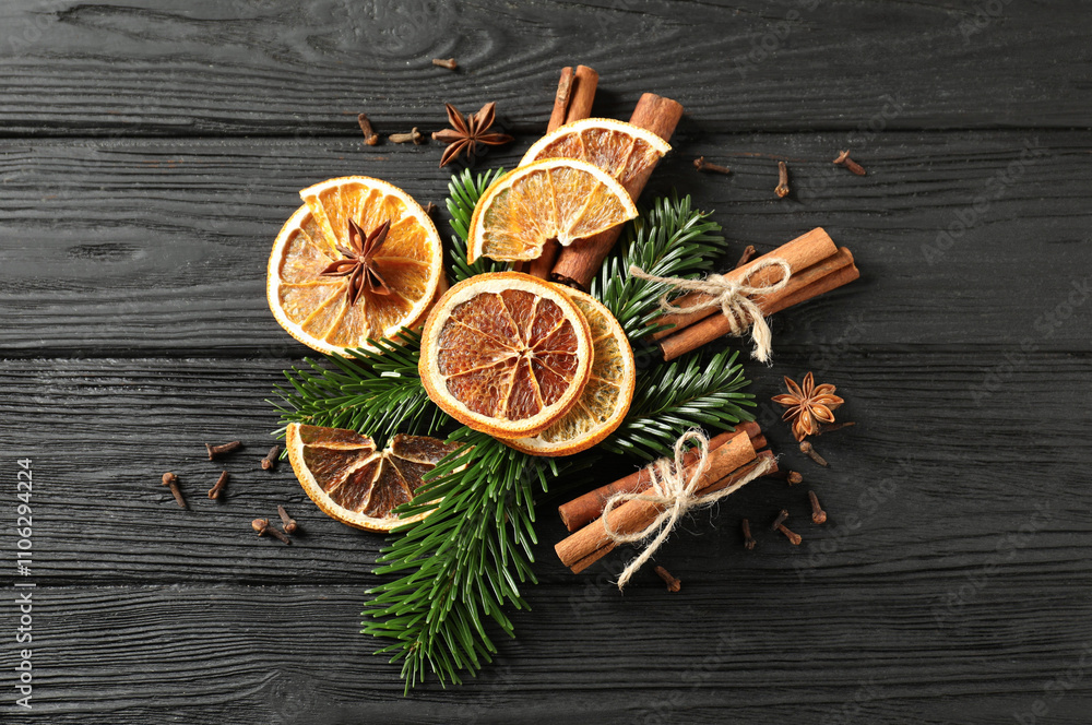 Different spices, dried orange slices and fir tree branches on black wooden table, flat lay. Christmas season Different spices, dried orange slices and fir tree branches on black wooden table, flat lay. Christmas season