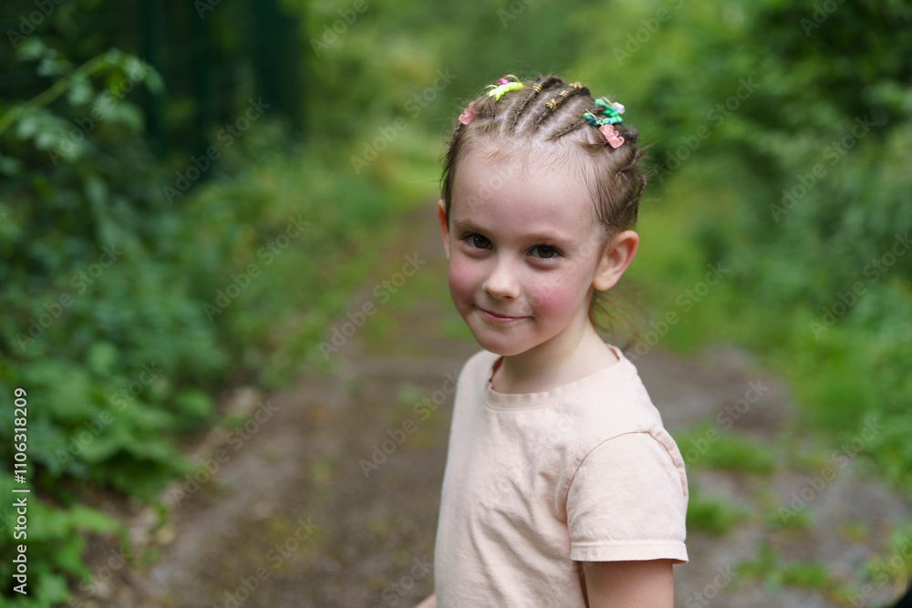 A cute little girl with dreadlocks and missing a front tooth is walking in the park in the summer. The concept of a cheerful, active, carefree child. A cute little girl with dreadlocks and missing a front tooth is walking in the park in the summer. The concept of a cheerful, active, carefree child.